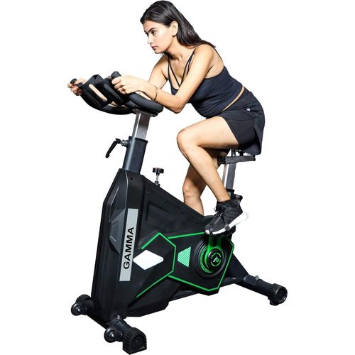 Commercial spin bike in black and green with a woman riding it in a racing posture — Electromart Uganda
