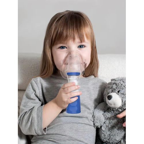 A young girl using the portable ultrasonic mesh nebuliser with a face mask on a sofa — Electromart Uganda